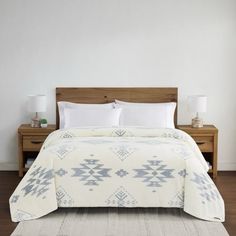 a bed with white sheets and pillows on top of a wooden headboard next to a night stand