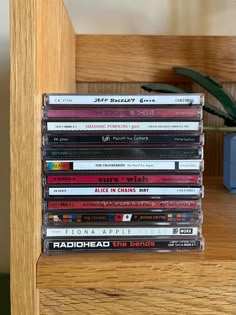 a stack of cds sitting on top of a wooden shelf