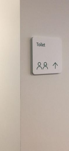 a white wall with a sign that says toilet and two arrows pointing in opposite directions