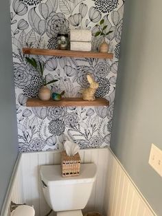 a white toilet sitting in a bathroom next to a wooden shelf filled with towels and other items