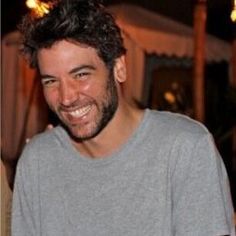 a man smiling and wearing a gray shirt