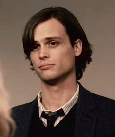 a young man in a suit and tie looking at the woman's face while she is talking to him