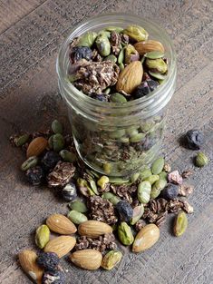 a glass jar filled with nuts and raisins on top of a wooden table