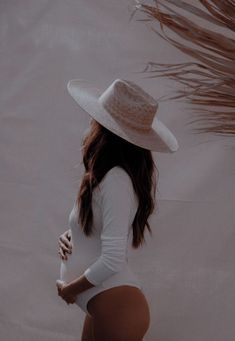 a woman in a white bodysuit and hat