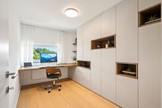 a home office with white cabinets and wood flooring