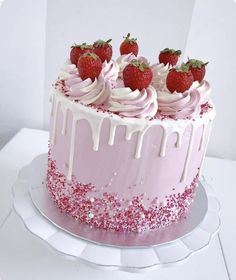 a pink cake with white icing and strawberries on top