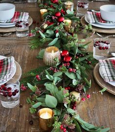 the table is decorated with greenery, berries and candles for christmas dinner tablescapes