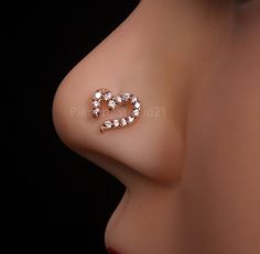 a close up view of a nose with a heart shaped diamond earring on it