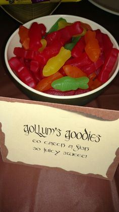 a bowl full of gummy bears sitting on top of a table next to a sign