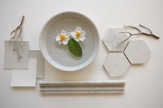 a white bowl with flowers in it next to hexagonal tiles and scissors on the table