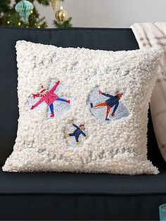 a decorative pillow on a couch in front of a christmas tree with snowflakes