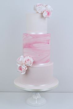 a white and pink wedding cake with flowers on top