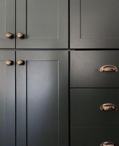 the cabinets are painted black and have brass handles