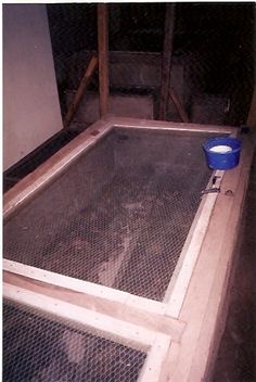 a blue bucket sitting on top of a wooden floor next to a caged in area