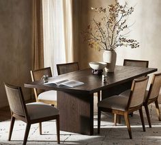 a dining room table with chairs and a vase filled with flowers on top of it