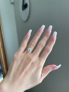 a woman's hand with white manicured nails and a diamond ring