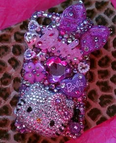 a cell phone covered in pink and purple sequins on a leopard print surface