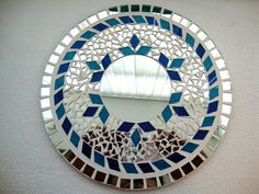 a round mirror with blue and white tiles on the bottom is hanging on a wall