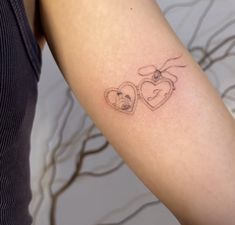 a woman's arm with two heart shaped tattoos on the left side of her arm