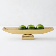 three green apples in a wooden bowl on a stand