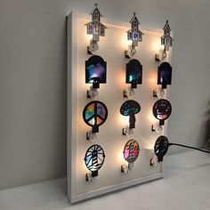 a wall mounted clock with many different clocks on it's face and lights around the clock