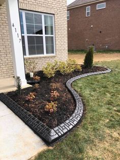 a brick walkway leading to a house with grass and bushes in front of the door