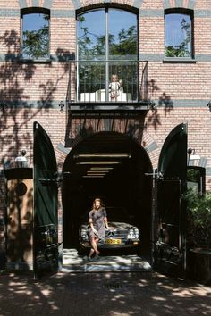 a woman sitting in the doorway of a brick building with an open car garage door