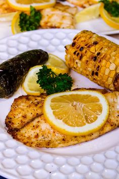 grilled fish, corn on the cob and lemon slices