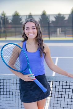 a woman holding a tennis racquet on top of a tennis court with net