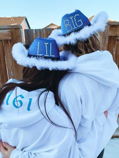 two people wearing matching sweatshirts and hats with numbers on the hood, back to back