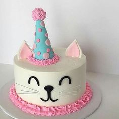 a birthday cake with a cat's face wearing a blue and pink party hat