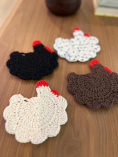 four crocheted chicken ornaments sitting on top of a wooden table