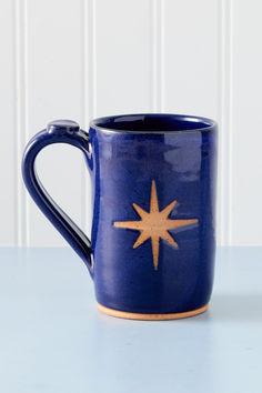 a blue coffee mug with a gold star on the outside and inside, sitting on a table