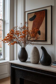 three vases with flowers in them sit on a table next to a fireplace mantel