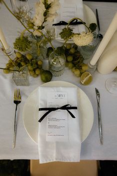 a place setting with white plates and silverware, napkins and flowers on the table