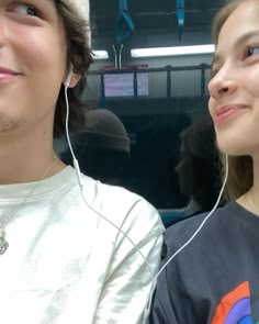 two people sitting next to each other with ear phones in their ears