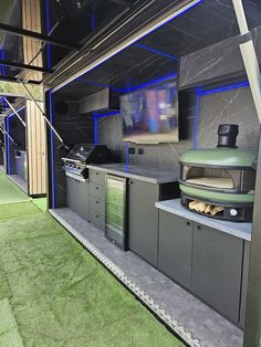 an outdoor kitchen with green grass on the ground and blue lights in the ceiling above it