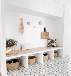 a white room with several baskets on the wall and a bench in front of it