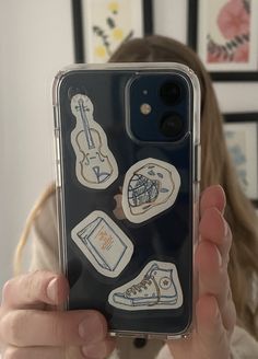 someone holding up their phone case with stickers on it