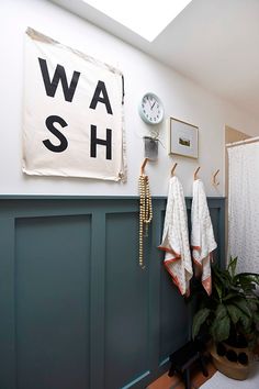 a bathroom with two towels hanging on the wall next to a plant and a clock