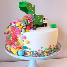 a white cake topped with lots of colorful candies and a green truck on top