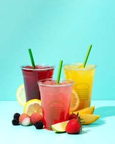 three drinks with strawberries, lemons and raspberries on a blue background