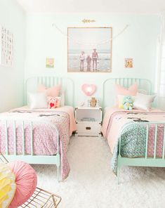 two twin beds with pink and green bedding in a bedroom next to each other