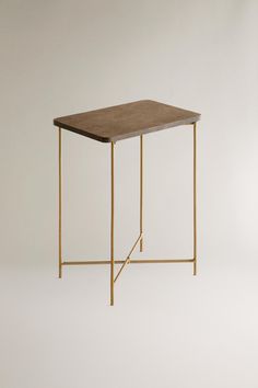 the side table is made from brass and has a wooden top with a square shaped edge