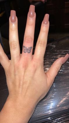 a woman's hand with a small butterfly tattoo on her left thumb and finger