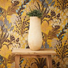 a vase sitting on top of a wooden table in front of a wallpapered background