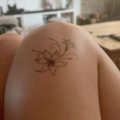 the back of a woman's shoulder with a flower tattoo on her left arm