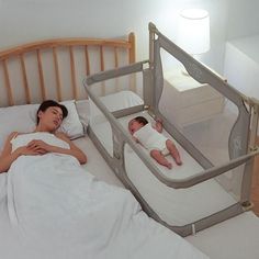 a woman laying in bed next to a baby with a crib on it's side