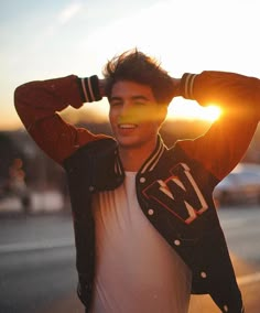 a young man with his hands on his head, standing in the street at sunset