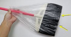 a hand holding a black and white umbrella wrapped in plastic with yellow arrows pointing to it